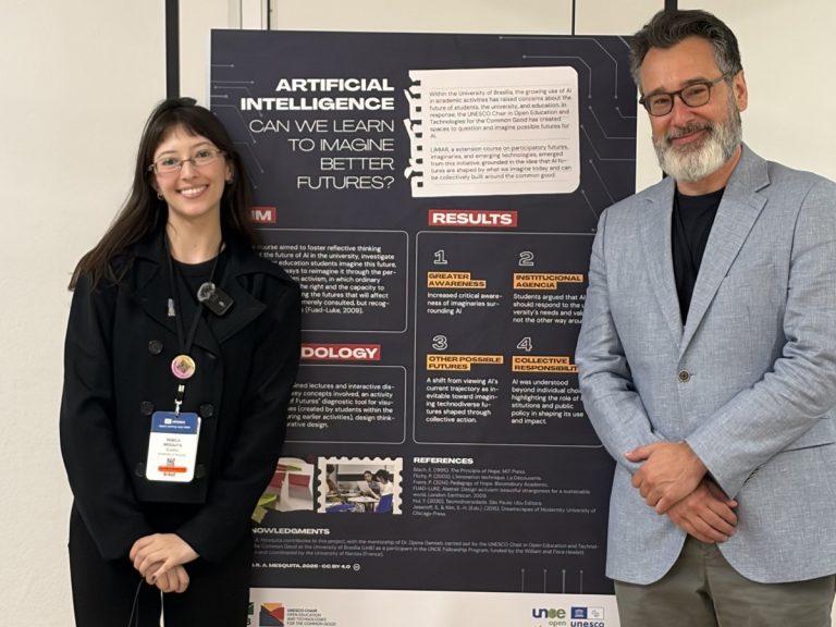 a bolsista Rebeca Mesquita e o coordenador Tel Amiel, junto ao pôster de apresentação da Cátedra na UNESCO Digital Learning Week 2026, em Paris.